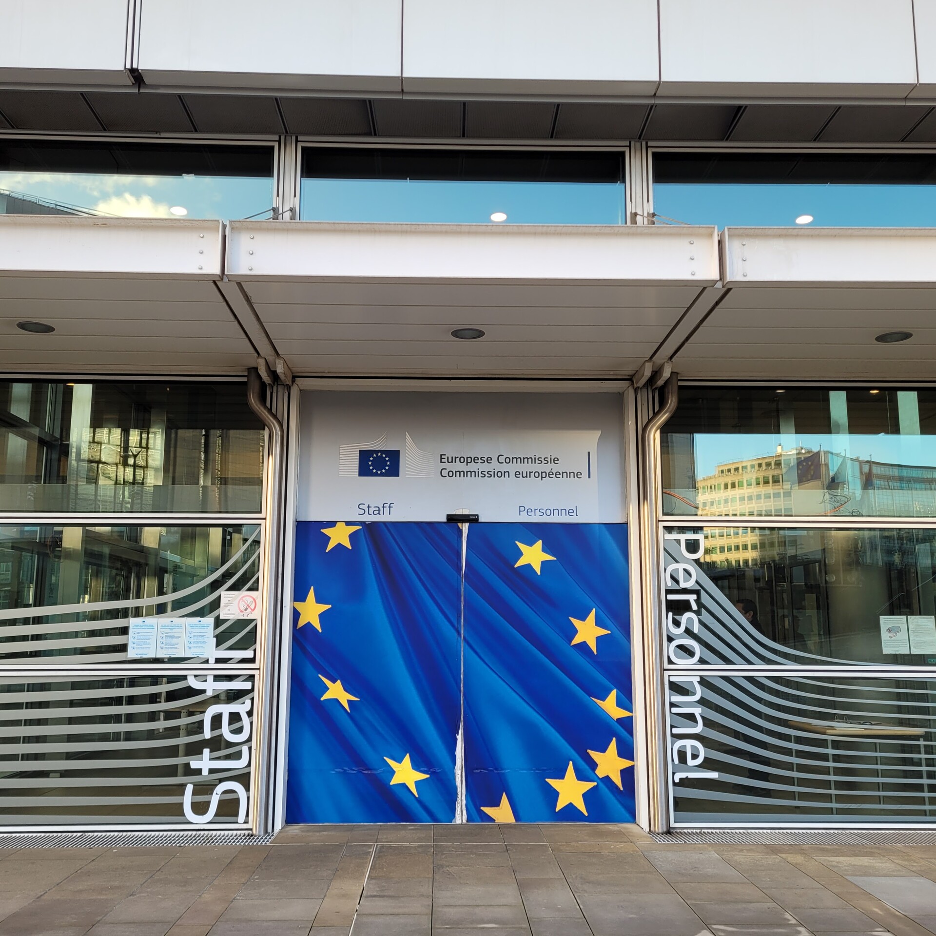 Eingang ins EU-Parlament, der durch die EU-Fahne verhängt ist. Links steht "Staff", rechts "Personnel" 